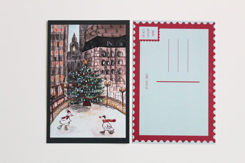 Postcard with an illustration of two ducks skating in front of a Christmas tree, wearing hats and scarves, in front of a city landscape. Pictured with the back of the postcard where a letter can be written and address lines.