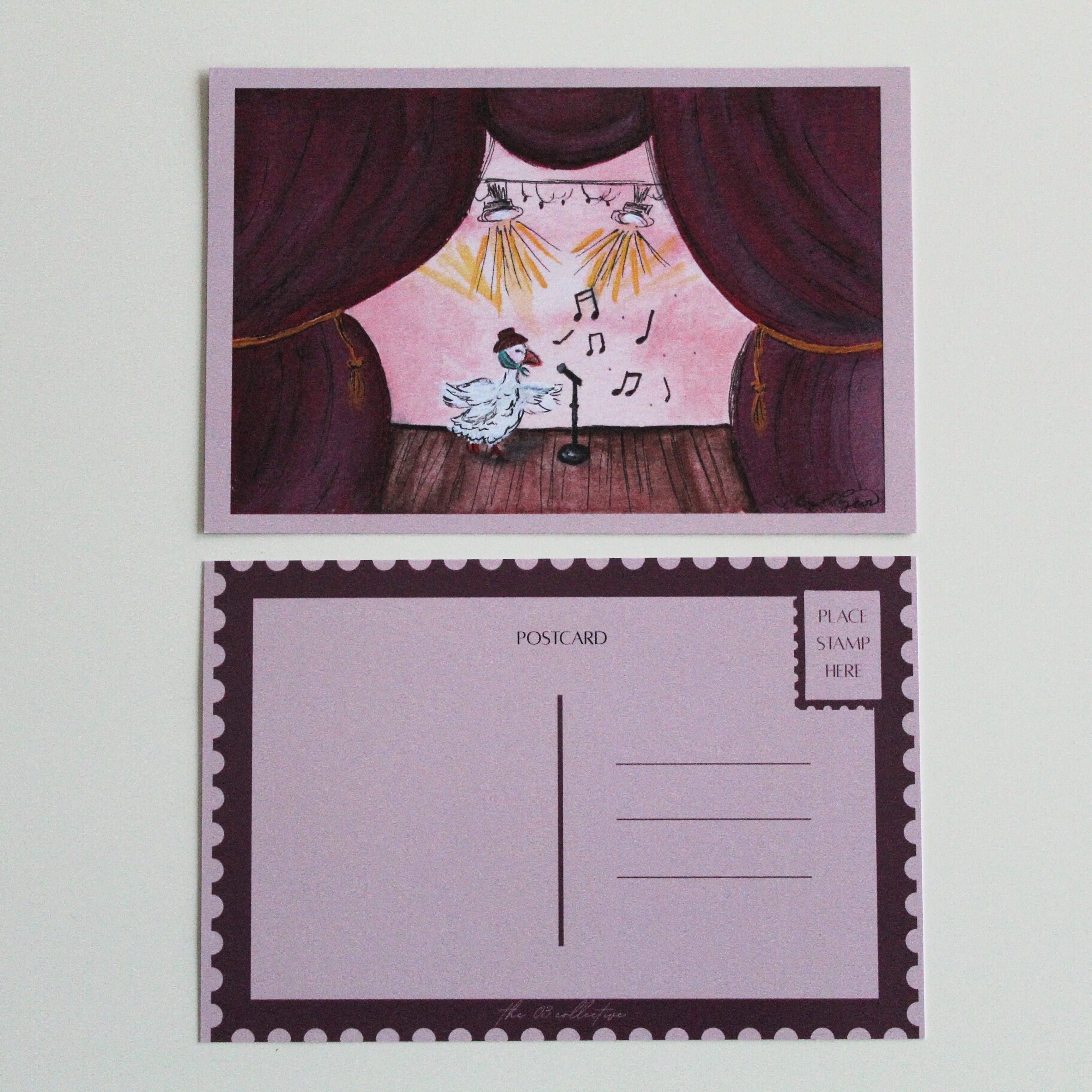 Postcard with an illustration of a duck performing on stage while wearing a brown hat and green scarf. The stage is made of brown wood and giant burgundy curtains with gold chords. Pictured with the back of the postcard where a letter can be written and address lines. 