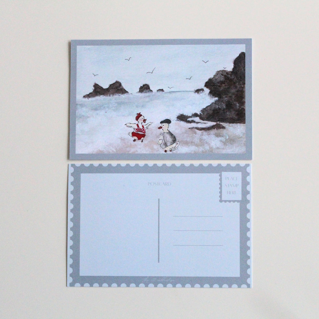 Postcard with an illustration of two ducks on a rocky and wavy beach, one wearing a red bathing suit and headband, and the other wearing a t-shirt and cap. Pictured with the back of the postcard where a letter can be written and address lines.