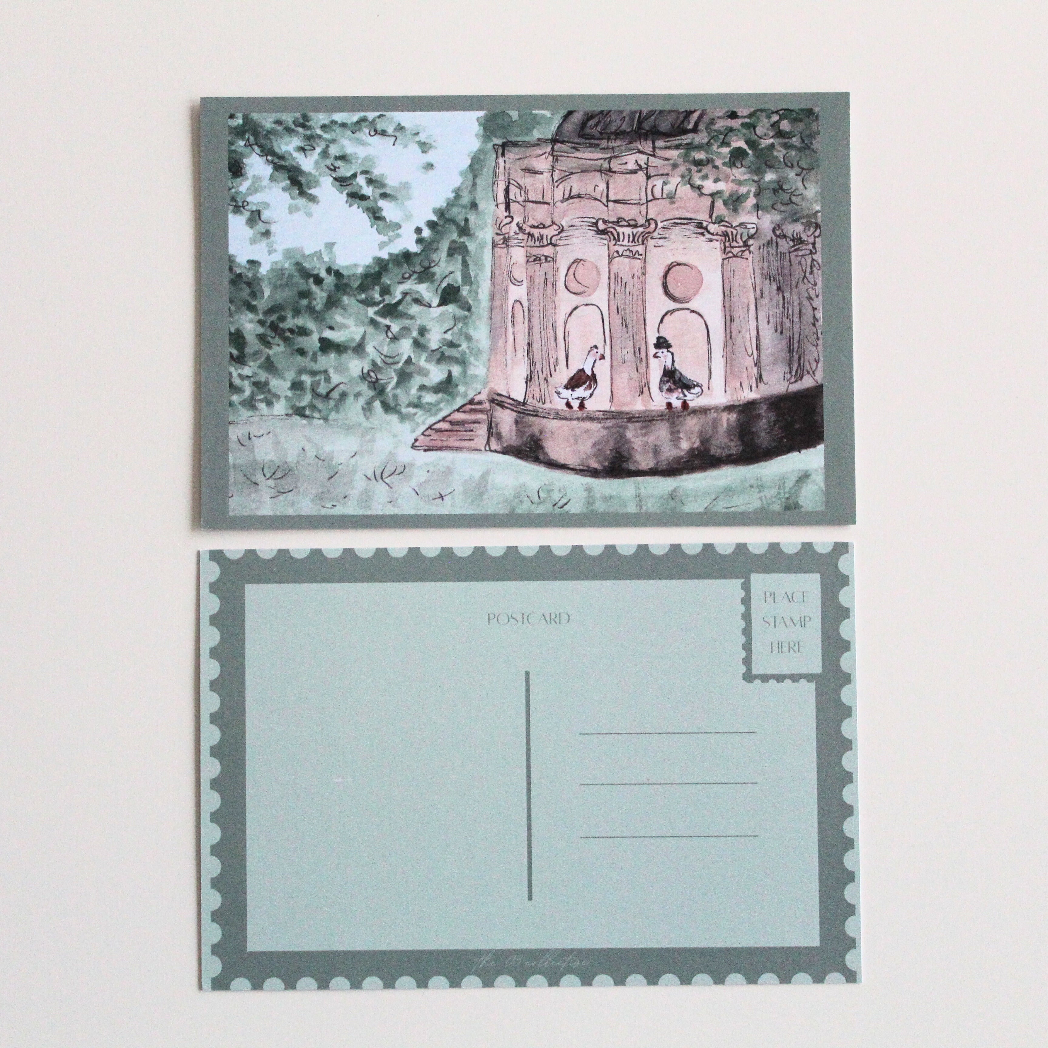 Postcard with an illustration of two ducks at the Temple of Apollo, one wearing a dress, and the other wearing a suit and hat, surrounded by leaves and trees.
Pictured with the back of the postcard where a letter can be written and address lines.